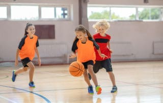 youth girls basketball players performing fun basketball drills