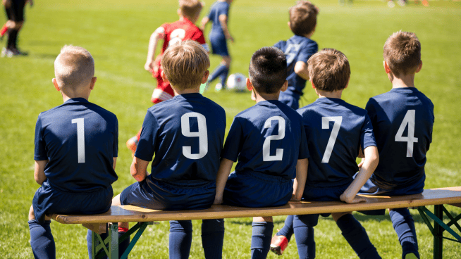 stack.com – riding the bench young male soccer athletes sitting on bench during a game